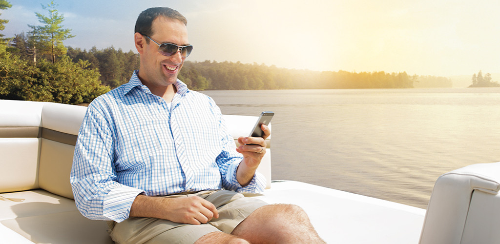 VV-header Man sits on a boat deck smiling at his phone